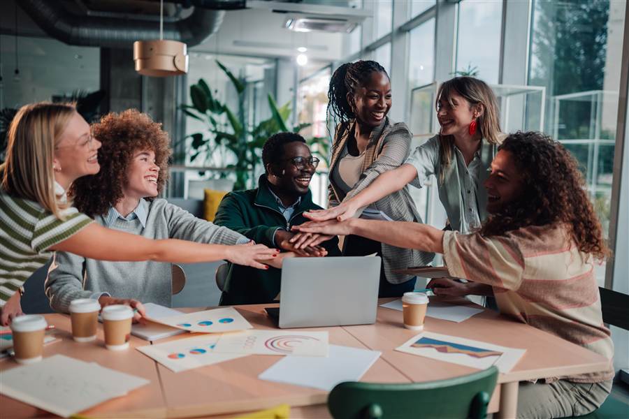 Small business team celebrating over a laptop and reports