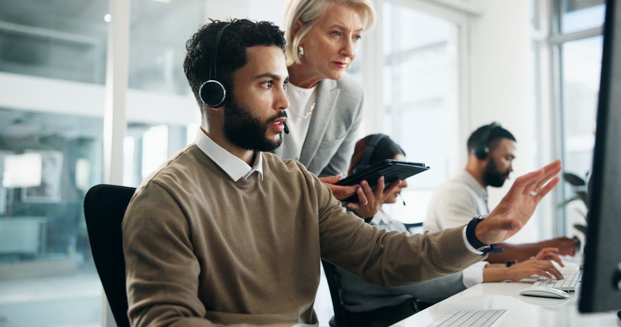 Helpdesk technician working alongside a colleague at a shared desk