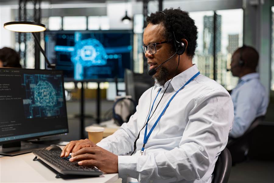 Helpdesk technician wearing a headset while working at a desk