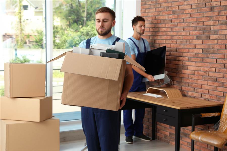 Movers carrying a box of retired office equipment and a monitor