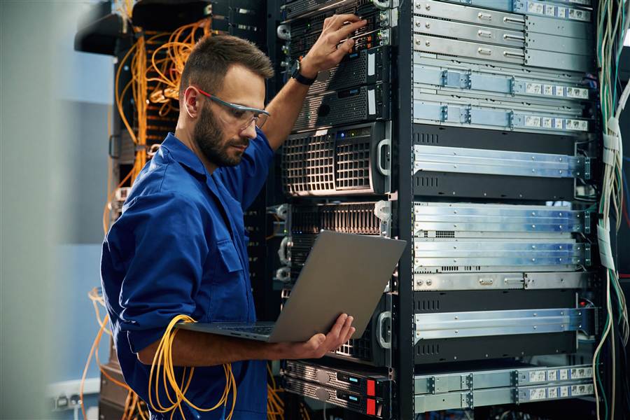 Technician with a laptop servicing a network server rack
