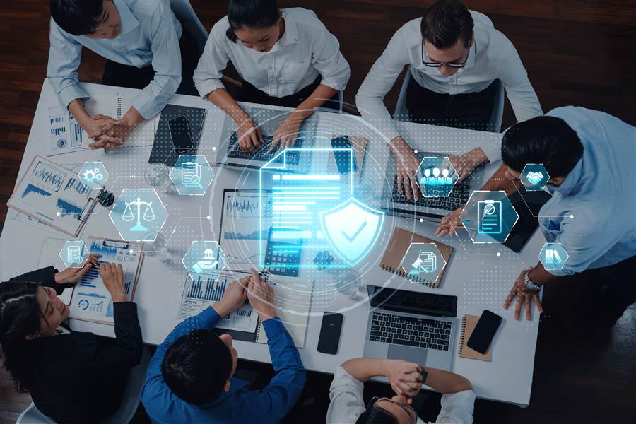 Business team reviewing compliance and IT management icons around a laptop