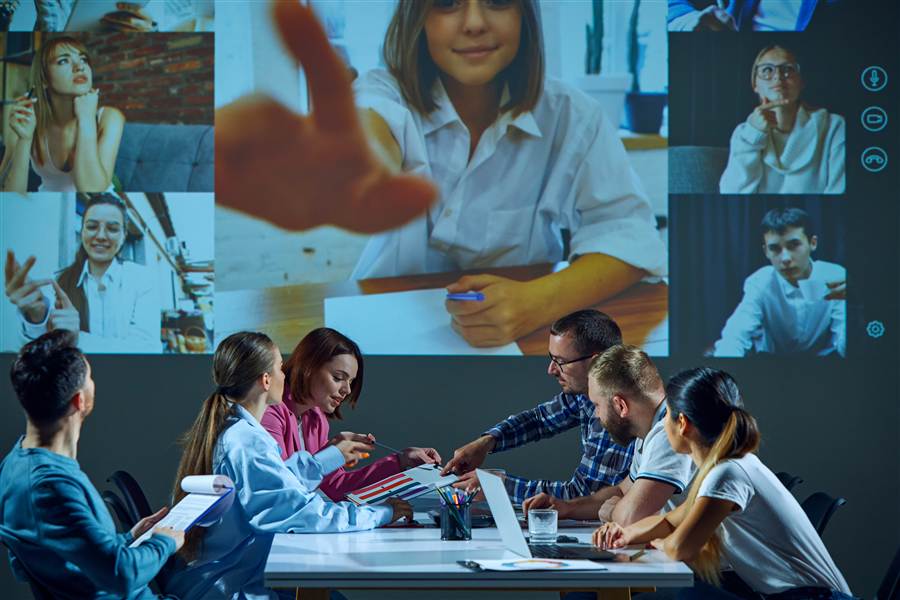 Team in a meeting room video conferencing with multiple remote participants