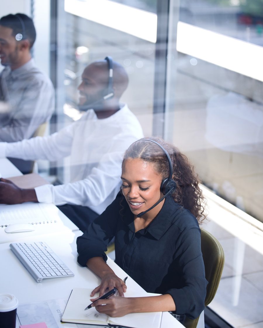 Service desk technician wearing a headset and taking notes